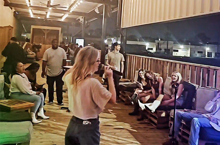 Person singing karaoke while friends cheer